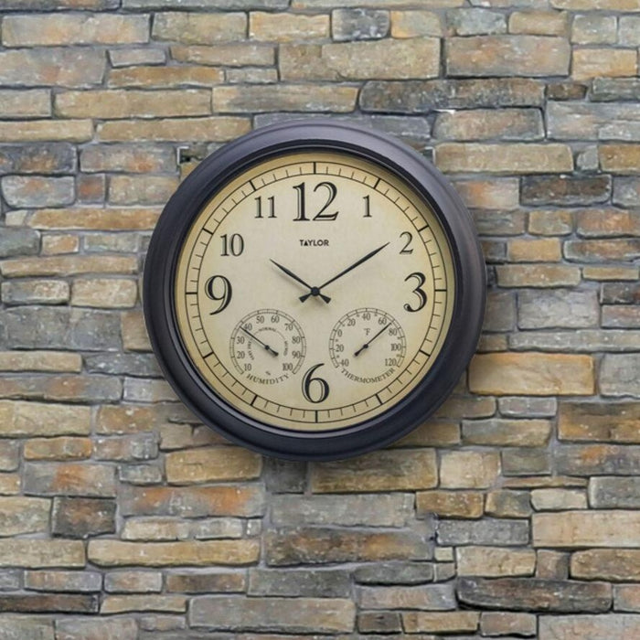 Bronze metal garden clock with hygrometer and thermometer mounted on a stone wall