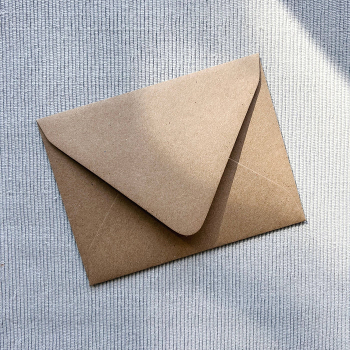 Kraft paper envelope with curved flap closure on textured neutral background