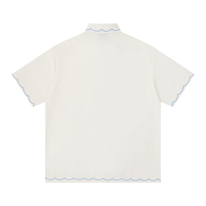 Cream oversized short sleeve shirt with blue scalloped trim on the collar, sleeves, and hem, shown from the back