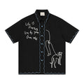 Black oversized short sleeve shirt with blue scalloped trim, handwritten text, and abstract greyhound embroidery