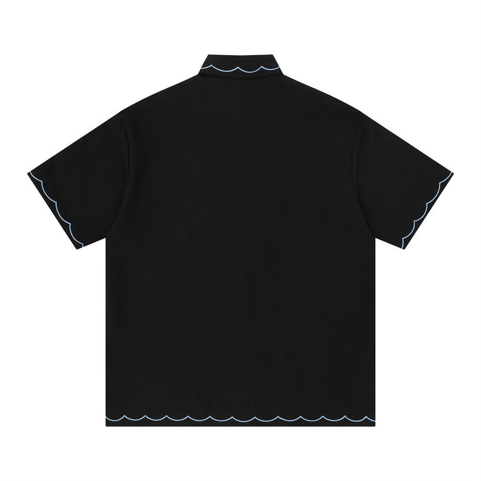 Black oversized short sleeve shirt with light blue scalloped trim on the collar, sleeves, and hem, shown from the back