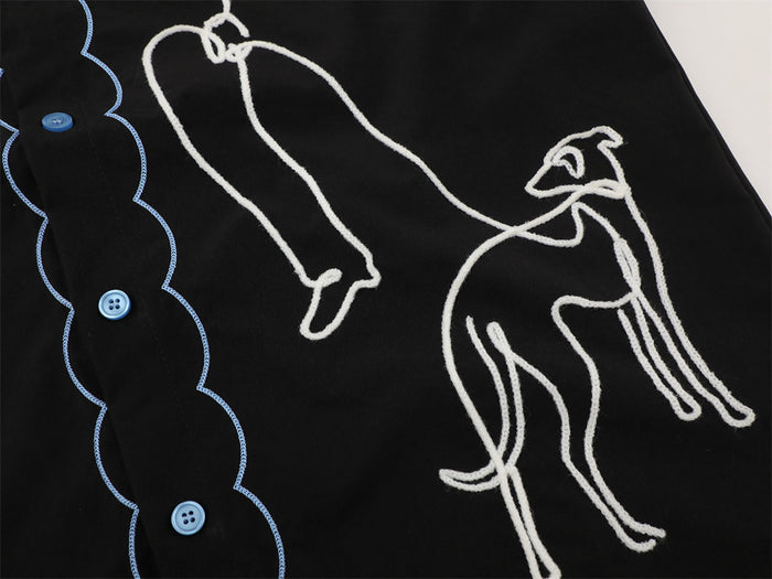 Black short sleeve shirt with blue buttons and white abstract greyhound embroidery, close-up streetwear design