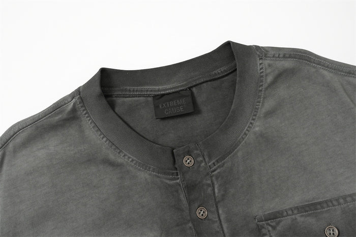 Close-up of a dark acid wash oversized Henley T-shirt with ribbed collar, button placket, and chest pocket detail