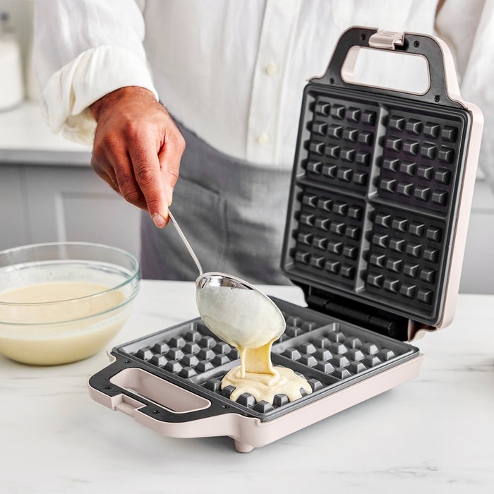 Person using a waffle maker with batter being poured into it