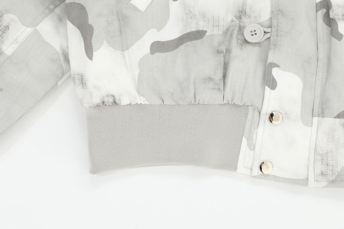 Close-up of jacket ribbed hem, snap buttons, and camouflage fabric