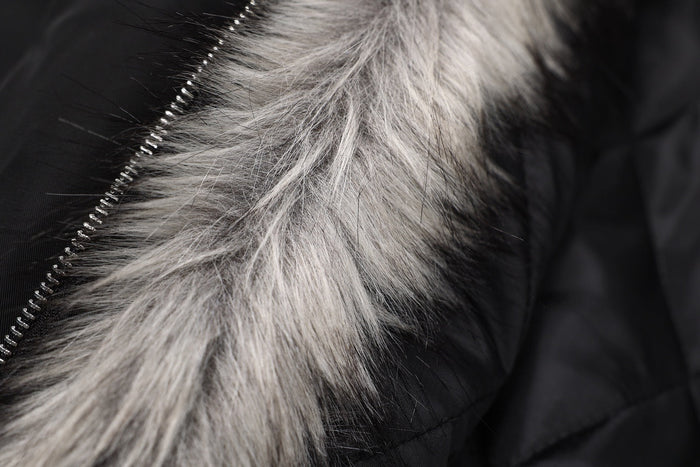 Close-up of gray faux fur hood trim beside black jacket zipper