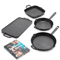 The Bobby Flay by GreenPan 4-Piece Cast Iron Set includes a grill pan, griddle, and two spacious skillets in black, shown on a white surface beside the “Bobby at Home” cookbook featuring the chef on the cover.