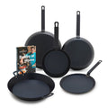Five-piece carbon steel cookware set with Bobby at Home cookbook on a white background.