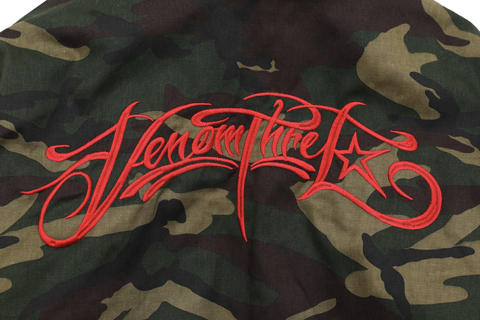 Red embroidered script on the back of a camo bomber jacket
