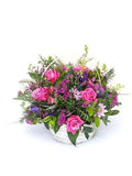 Basket of pink and blue flowers arranged in a celebration theme, featuring roses and assorted seasonal blooms in lush greenery.