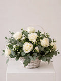 White rose and eucalyptus flower basket with wax flower in whitewashed wicker basket