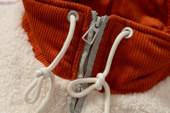 Close-up of orange ribbed collar with cream drawcords and silver zipper pull