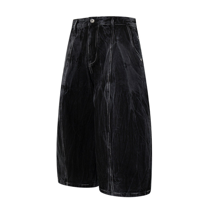 Black wide-leg denim shorts shown at a slight side angle with crinkled wash and contrast seams