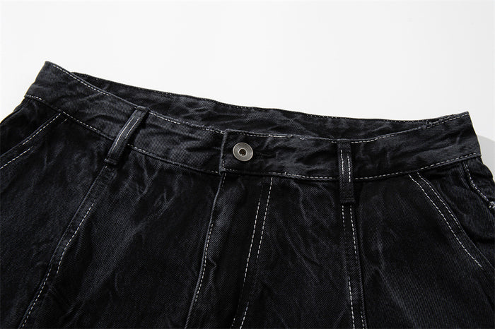 Close-up of the front waistband on black denim shorts with button closure and belt loops