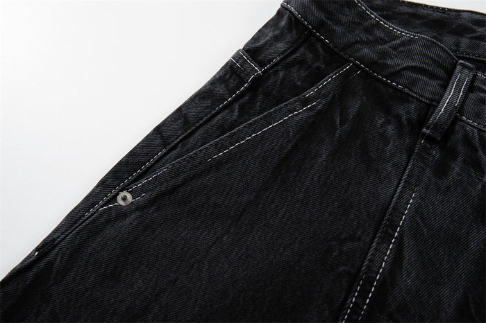 Close-up of the side seam and pocket area on black crinkle-washed denim shorts