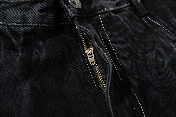 Close-up of the front fly zipper and waistband on black denim shorts