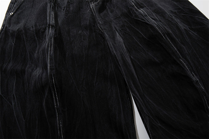 Close-up of the front leg panels on black denim shorts with crinkled texture and stitching