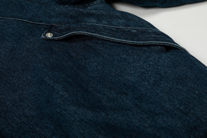 Close-up of deep indigo denim sleeve with snap tab detail