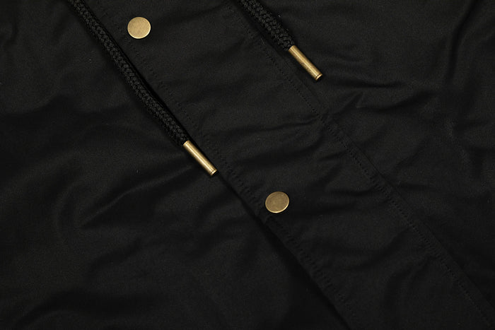 Close-up of black bomber jacket front with gold snap buttons and diagonal seam detail