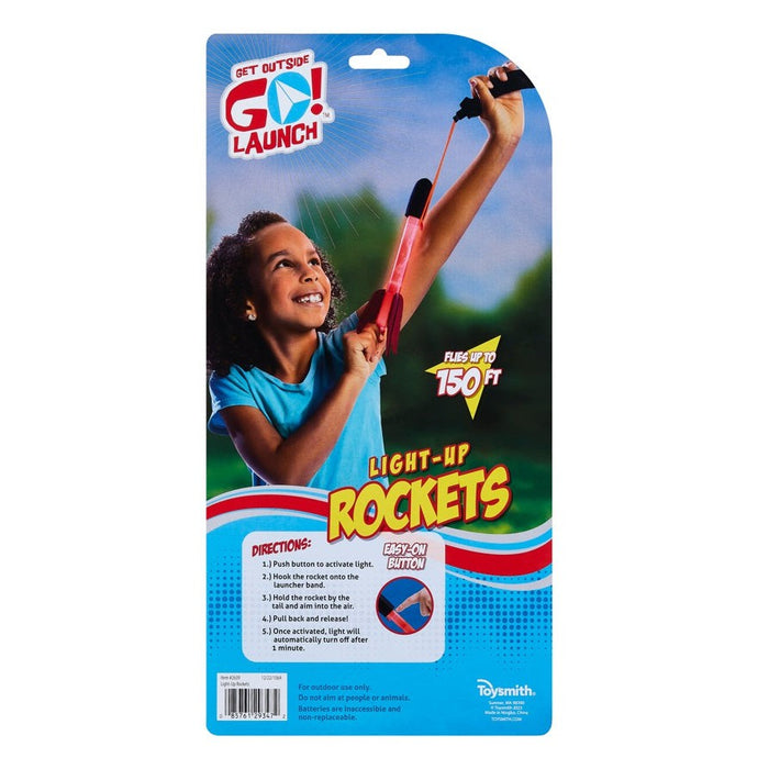 A smiling child launches a red GO! Launch Light-Up Rocket up to 150 ft in the backyard using the handheld launcher. The package displays directions and GO! Launch branding.