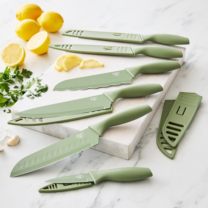 Sage green 6-piece cutlery set with covers on marble counter, surrounded by lemons, parsley, and garlic.