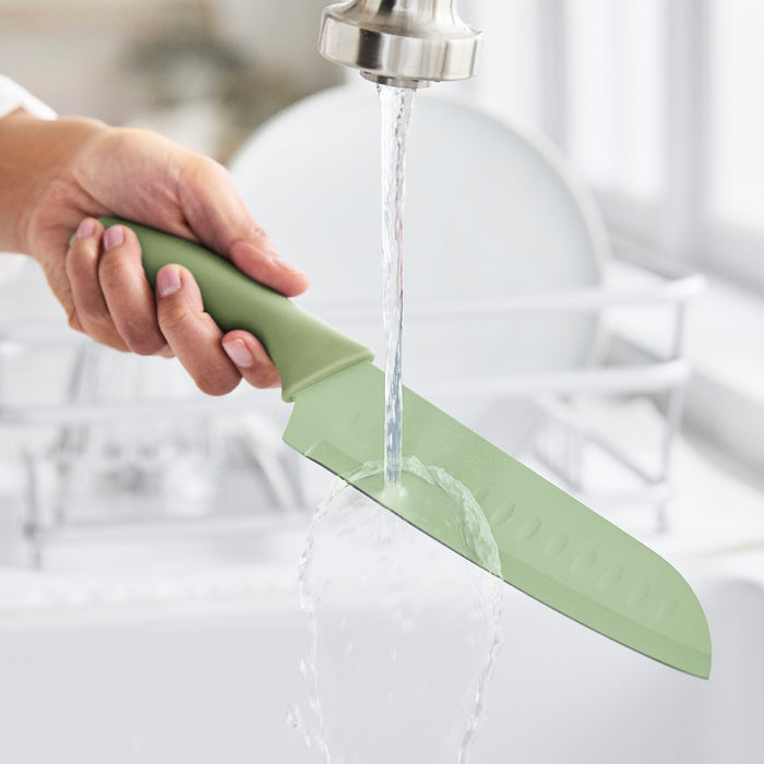 Hand rinsing a GreenLife knife from 6-piece cutlery set under running water near a drying rack.