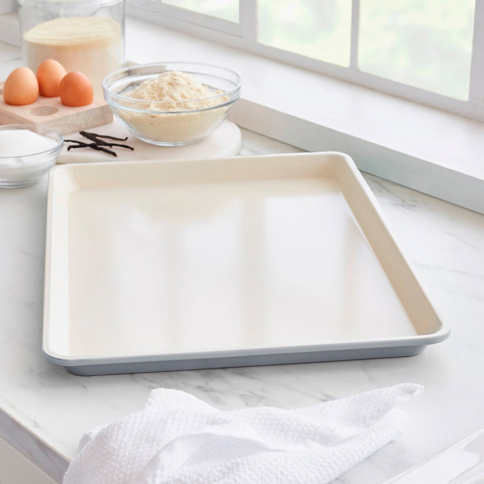 Quartz gray ceramic cookie sheet on a kitchen counter with baking ingredients in the background.