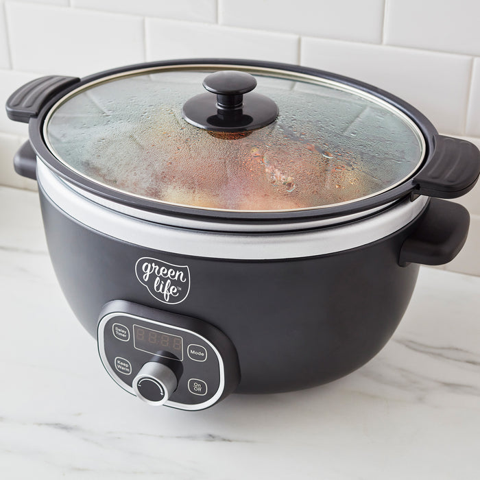 Black slow cooker with glass lid on a white countertop