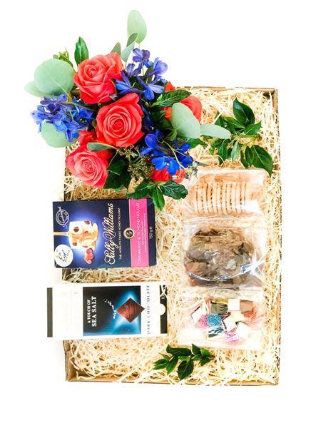 Gift box with orange roses, strawberry biscuits, nougat, biltong, liquorice, and Lindt chocolate for a delightful treat.