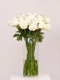 Bouquet of white flowers in a clear vase on a light gray background