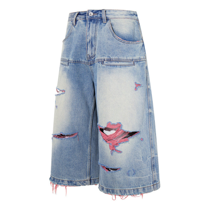 Front view of washed blue distressed wide-leg denim shorts with ripped details and pink thread