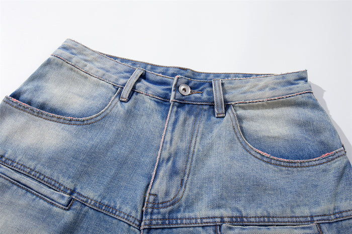 Close-up of the front waistband, button closure, and pocket edges on washed blue denim shorts