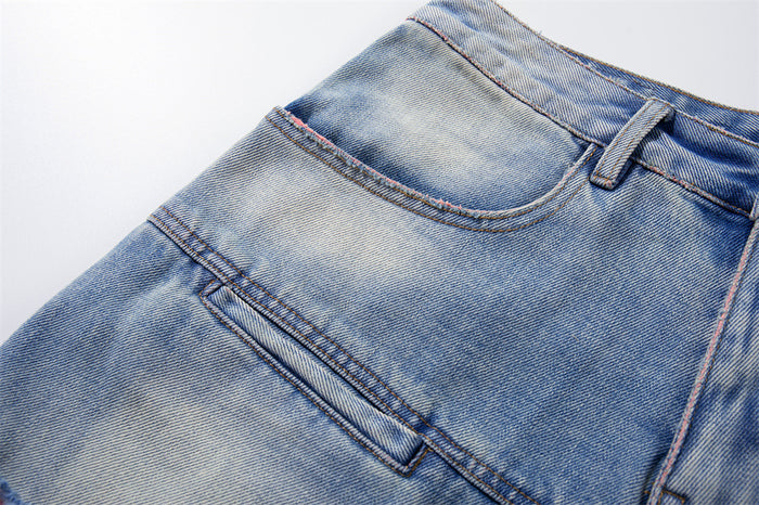 Close-up of front pocket and seam detail on washed blue denim shorts with pink stitching