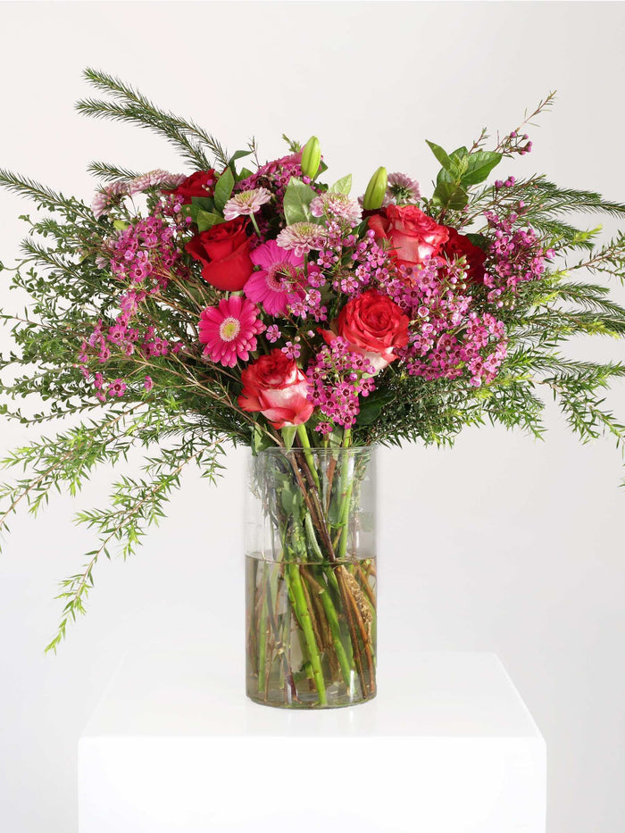 Vibrant pink flower bouquet with roses, penny gum, and greenery arranged elegantly in a vase, ideal for any occasion.