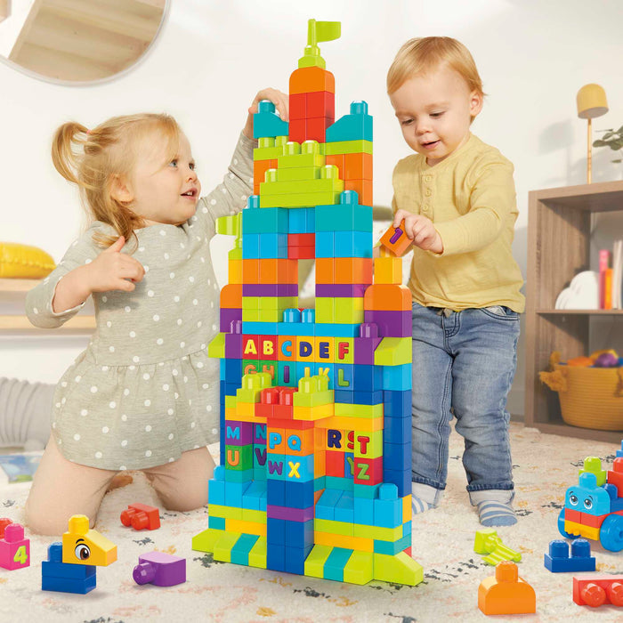 Two children build a tall tower in a bright playroom using the MEGA Bloks Even Bigger Building Bag by Mega Bloks. Scattered blocks let them develop fine motor skills as they play, build, and explore together.