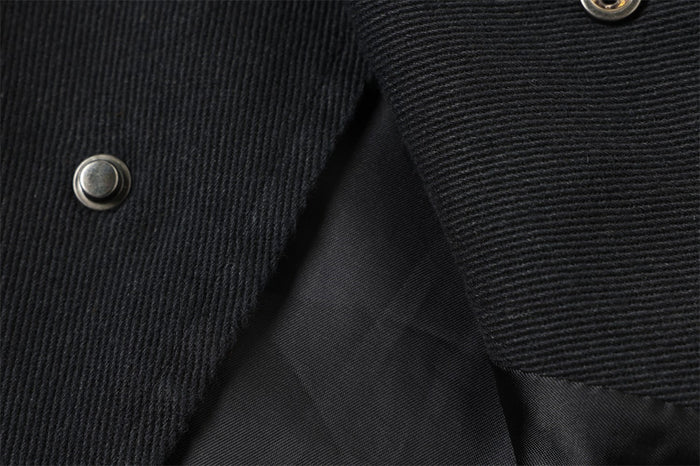 Close-up of diagonal snap front on black textured jacket fabric