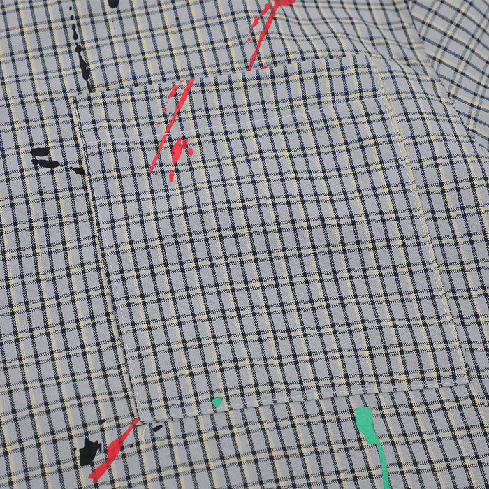 Close-up of front chest pocket on gray plaid shirt with red and teal paint splatter