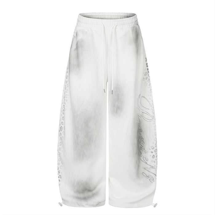 Men's wide leg tie-dye sweatpants in white with leopard print panels and cursive script graphic on the leg