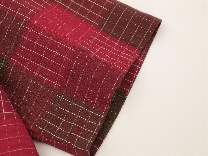 Close-up of a red and brown plaid short sleeve button-up shirt with oversized streetwear style and mosaic grid pattern