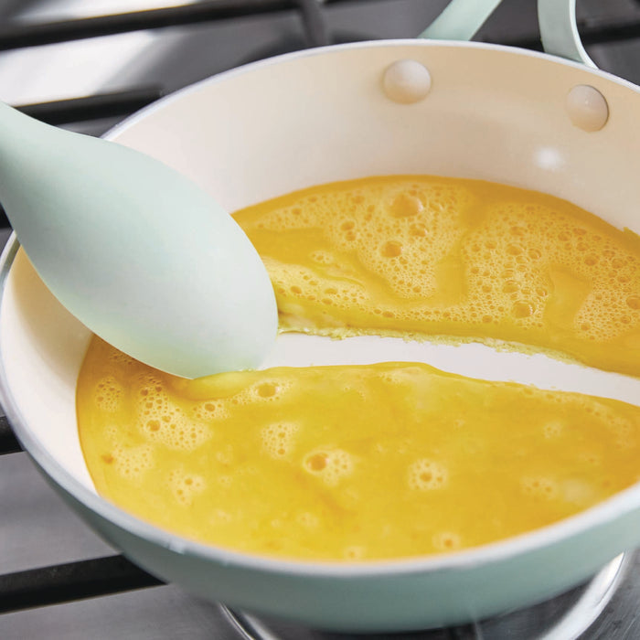Eggs in a green frypan on a stove