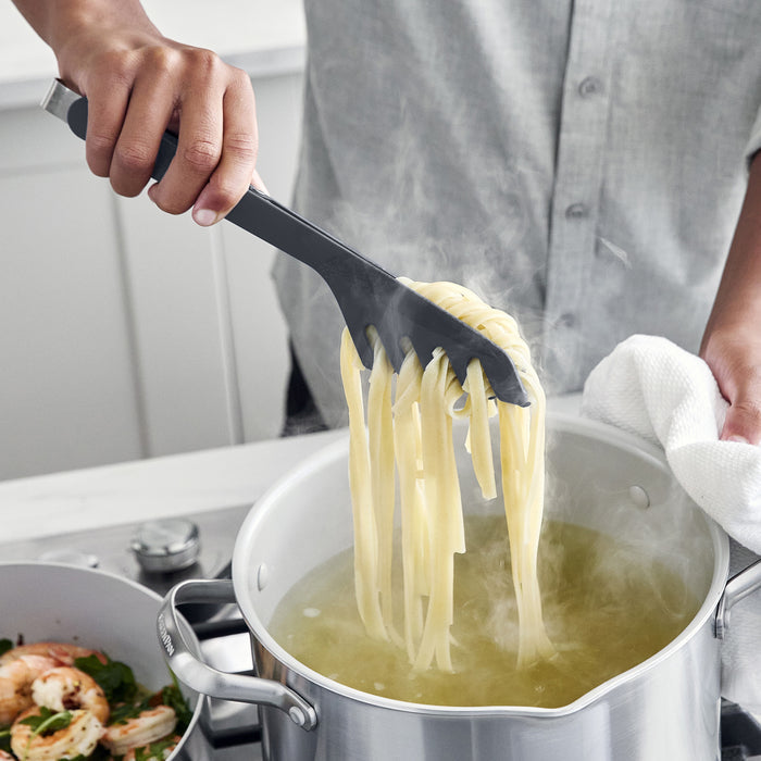 Person using silicone tongs to pull pasta out of a stockpot