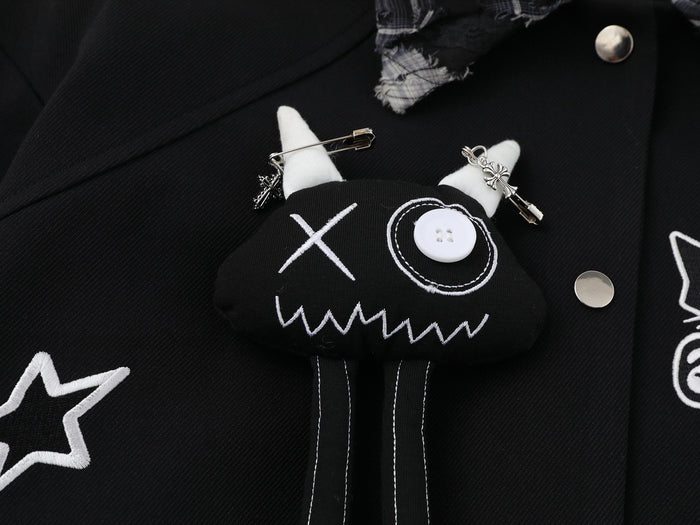 Close-up of cat face embroidery with button eye, white horns and hanging stitched legs