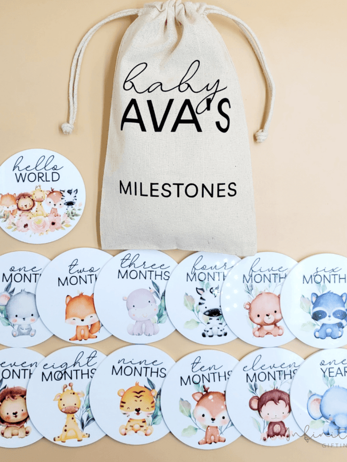 Personalised baby milestone disc set with 12 monthly acrylic discs and 'Hello World' disc, cotton bag included.
