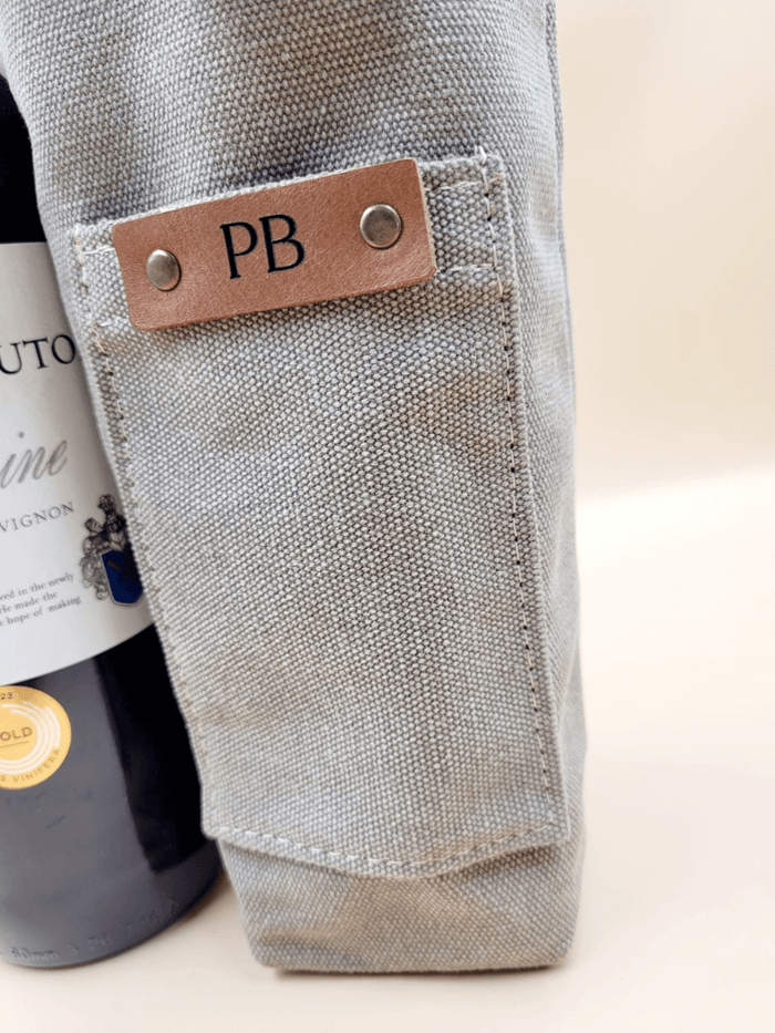 Personalised canvas leather wine carrier with initials PB, featuring a bottle and elegant craftsmanship.