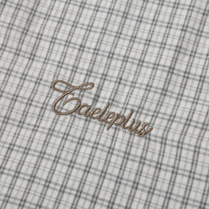 Brown embroidered logo on light gray plaid shirt front
