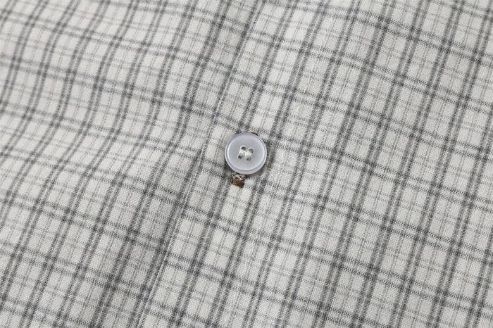Close-up of a shirt button on light gray plaid fabric
