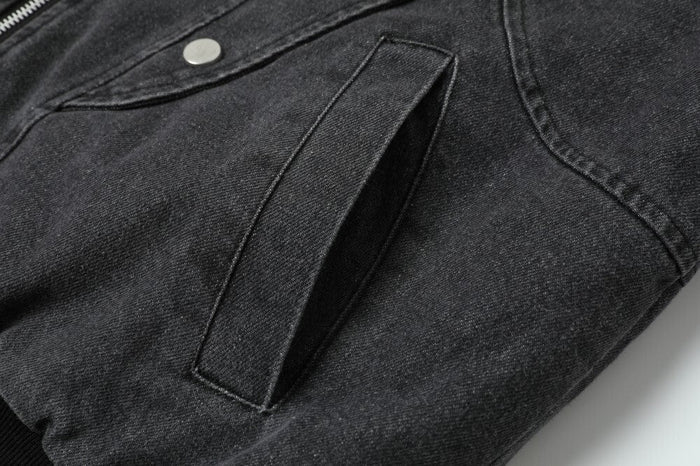 Close-up of a charcoal denim jacket pocket with angled opening detail
