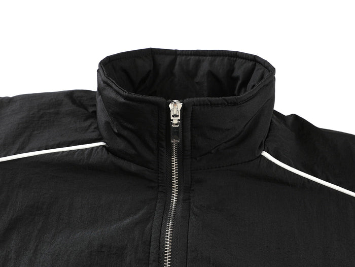 Close-up of black track jacket collar and front zipper with white shoulder piping