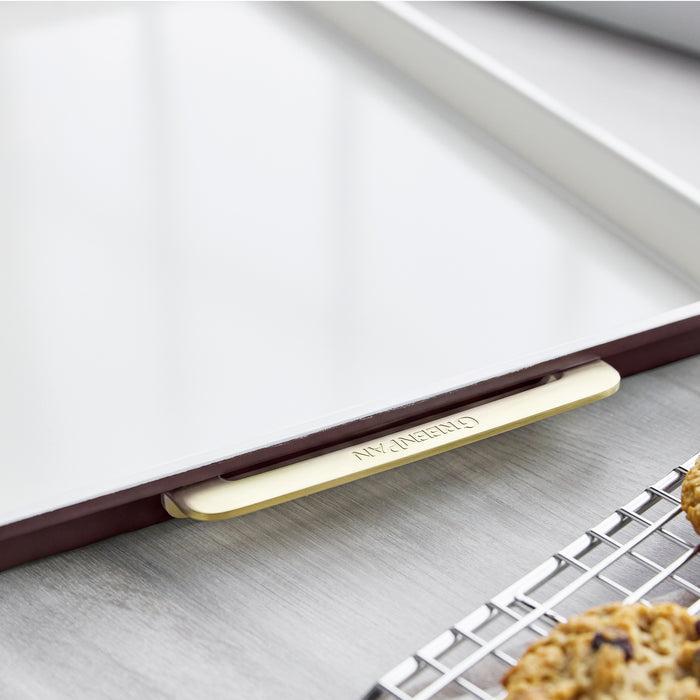 Bordeaux Reserve 13″ x 18″ half sheet pan with a white interior and gold-toned metal handle.