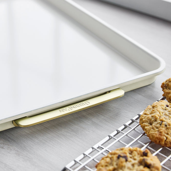 Cream half sheet pan with matching cooling rack, both holding cookies on a gray countertop.